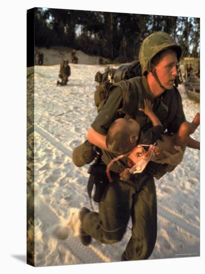 US Marine Medic Running Along Beach with Injured Vietnamese Infant under Fire During Vietnam War-Paul Schutzer-Stretched Canvas