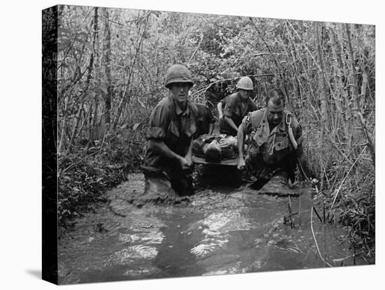 US Soldiers Carry a Wounded Comrade Through a Swampy Area in Vietnam, 1969-null-Stretched Canvas