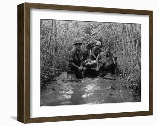 US Soldiers Carry a Wounded Comrade Through a Swampy Area in Vietnam, 1969-null-Framed Photo