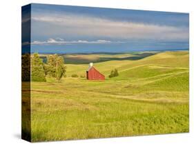 USA, Idaho, Palouse. Red barn with dark clouds and warm light-Terry Eggers-Stretched Canvas