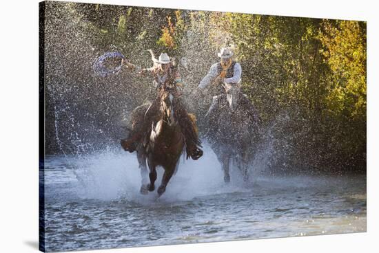 USA, Wyoming, Shell, The Hideout Ranch, Cowboy and Cowgirl on Horseback Running through the River-Hollice Looney-Stretched Canvas