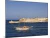 Valletta, A Fishing Boat Motors Out of the Entrance to the Grand Harbour Past Ricasoli Point, Malta-John Warburton-lee-Mounted Photographic Print