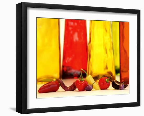 Various Types of Peppers in Front of Red & Yellow Bottles-Monica Varella-Framed Photographic Print