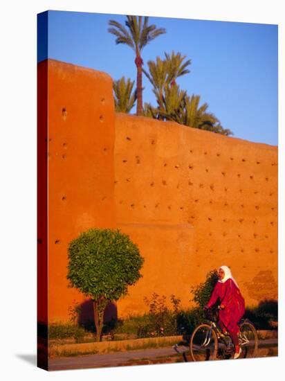 Veiled Woman Bicycling Below Red City Walls, Marrakech, Morocco-Merrill Images-Stretched Canvas