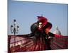 Venice, Veneto, Italy, a Mask in Costume on the Bacino Di San Marco with the Cupola of Santa Maria -Ken Scicluna-Mounted Photographic Print