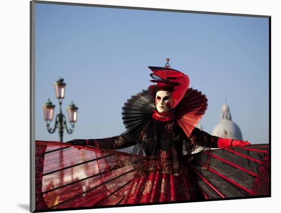 Venice, Veneto, Italy, a Mask in Costume on the Bacino Di San Marco with the Cupola of Santa Maria -Ken Scicluna-Mounted Photographic Print