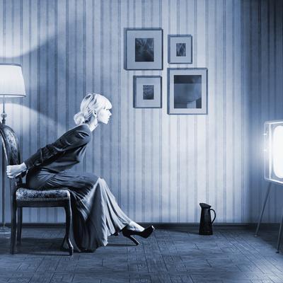 Young Woman Sitting on a Chair in Vintage Interior and Watching Retro TV