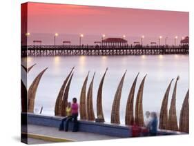 Waterfront Scene at Huanchaco in Peru, Locals Relax Next to Totora Boats Stacked Along the Beach-Andrew Watson-Stretched Canvas