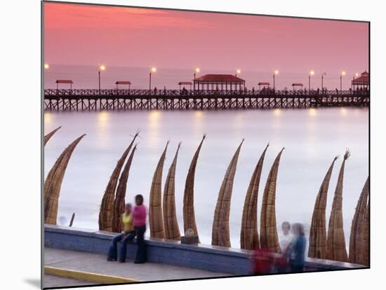 Waterfront Scene at Huanchaco in Peru, Locals Relax Next to Totora Boats Stacked Along the Beach-Andrew Watson-Mounted Photographic Print