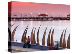 Waterfront Scene at Huanchaco in Peru, Locals Relax Next to Totora Boats Stacked Along the Beach-Andrew Watson-Stretched Canvas