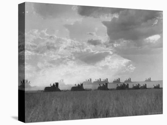 Wheat Harvest Time with Two Lines of Combines Lining Up in Field with Threatening Sky-Joe Scherschel-Stretched Canvas