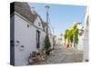 Whitewashed trulli houses along street in the old town, Alberobello, Puglia-Karen Deakin-Stretched Canvas