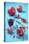 Whole and Sliced Pomegranate and Glass of Pomegranate Juice on Turquoise Wooden Table-Jana Ihle-Stretched Canvas