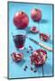 Whole and Sliced Pomegranate and Glass of Pomegranate Juice on Turquoise Wooden Table-Jana Ihle-Mounted Photographic Print