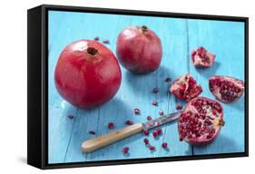 Whole and Sliced Pomegranates on Turquoise Wooden Table-Jana Ihle-Framed Stretched Canvas