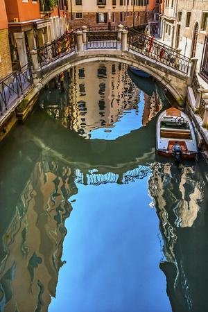 Colorful small canal and bridge creates beautiful reflections in Venice, Italy