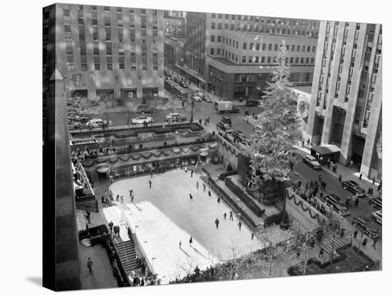 With the Famed Rockefeller Center Christmas Tree Rising Above Them, Skaters Glide on the Ice-null-Stretched Canvas