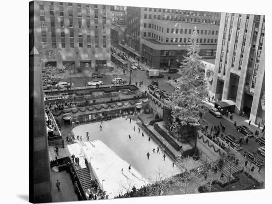 With the Famed Rockefeller Center Christmas Tree Rising Above Them, Skaters Glide on the Ice-null-Stretched Canvas