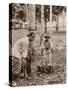 Woman and Young Boy Tap Rubber Trees in Malaya and Collect the Sap in Buckets-null-Stretched Canvas