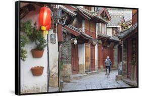 Woman cycling along alleyway, Lijiang (UNESCO World Heritage Site), Yunnan, China-Ian Trower-Framed Stretched Canvas