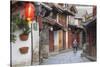 Woman cycling along alleyway, Lijiang (UNESCO World Heritage Site), Yunnan, China-Ian Trower-Stretched Canvas