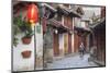 Woman cycling along alleyway, Lijiang (UNESCO World Heritage Site), Yunnan, China-Ian Trower-Mounted Photographic Print