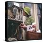 Woman in a Green Floppy Hat and Green Dress Browses in a Shop Selling Various Mirrors and Ornaments-null-Stretched Canvas