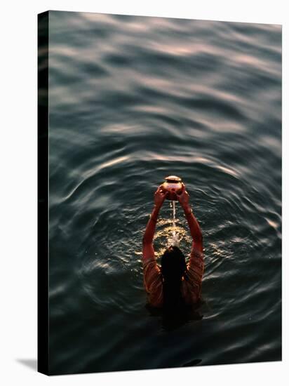 Woman Pouring Water During Morning Puja on Ganges, Varanasi, India-Anthony Plummer-Stretched Canvas