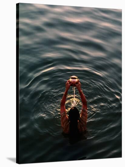 Woman Pouring Water During Morning Puja on Ganges, Varanasi, India-Anthony Plummer-Stretched Canvas