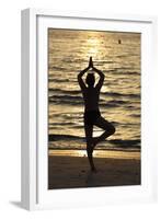 Woman practising yoga meditation on beach at sunset as concept for silence and relaxation-Godong-Framed Photographic Print