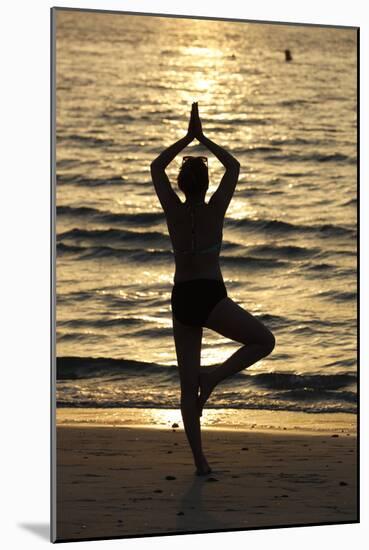 Woman practising yoga meditation on beach at sunset as concept for silence and relaxation-Godong-Mounted Photographic Print