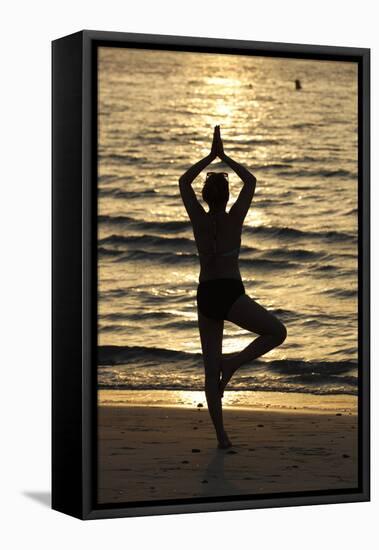 Woman practising yoga meditation on beach at sunset as concept for silence and relaxation-Godong-Framed Stretched Canvas