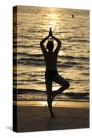 Woman practising yoga meditation on beach at sunset as concept for silence and relaxation-Godong-Stretched Canvas