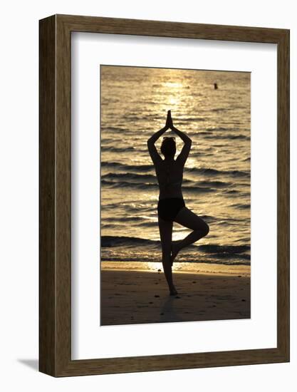 Woman practising yoga meditation on beach at sunset as concept for silence and relaxation-Godong-Framed Photographic Print
