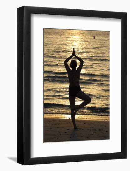 Woman practising yoga meditation on beach at sunset as concept for silence and relaxation-Godong-Framed Photographic Print