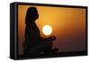 Woman practising yoga pose and meditation at sunset as concept for silence and relaxation-Godong-Framed Stretched Canvas