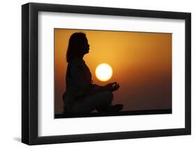 Woman practising yoga pose and meditation at sunset as concept for silence and relaxation-Godong-Framed Photographic Print