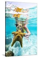 Woman showing a yellow starfish underwater in the tropical lagoon, Zanzibar, Tanzania-Roberto Moiola-Stretched Canvas