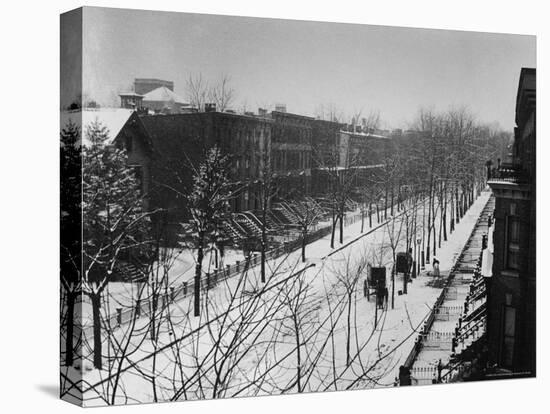 Woman sweeps snow off a snow-covered street lined with brownstones near two horse-drawn buggies.-George B^ Brainerd-Stretched Canvas