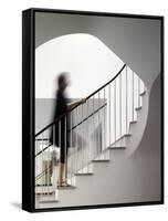 Woman walking up staircase holding handrail-John Edward Linden-Framed Stretched Canvas