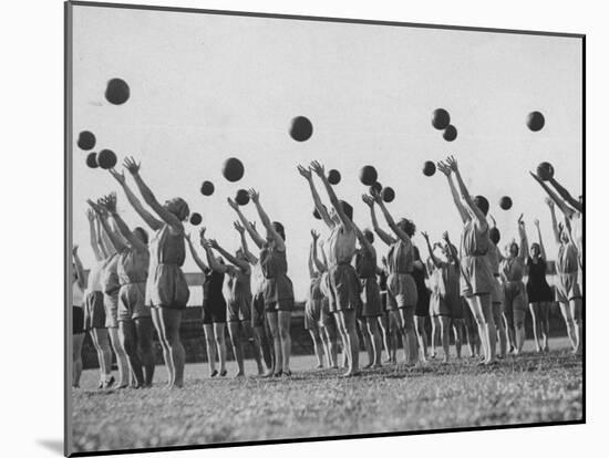 Women's Gym Class with Rows of Women Throwing Balls Into Air in Unison-null-Mounted Photographic Print