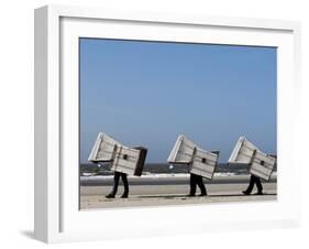 Workers Carry Beach Chairs Along the Beach of St. Peter-Ording at the North Sea, Northern Germany-null-Framed Photographic Print