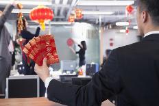 Businessman Holding Red Envelopes and Coworkers Hanging Decorations for Chinese New Year-XiXinXing-Laminated Photographic Print