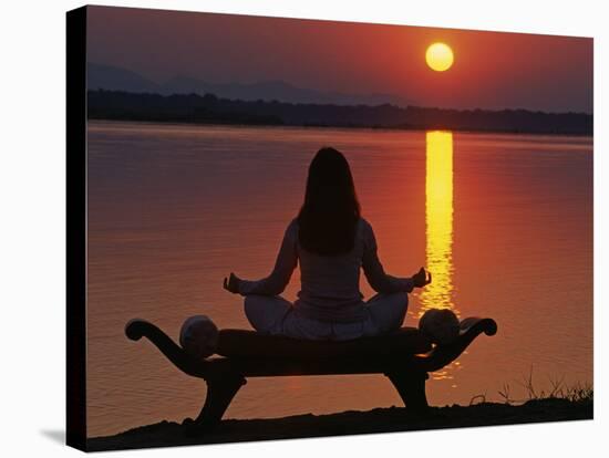 Yoga on a Saddle Bench Watching the Sun Go Down across the Zambesi River, Zambia-John Warburton-lee-Stretched Canvas