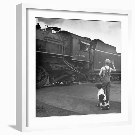 Young Boy and His Dog Standing at the Crossing as a Train Rides Through-Myron Davis-Framed Photographic Print
