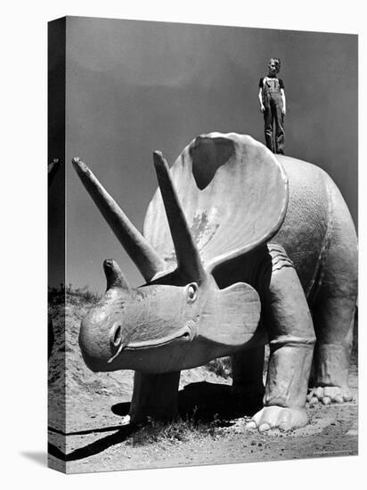 Young Boy Standing Atop Large Statue of Dinosaur in "Dinosaur Park" Tourist Attraction-Alfred Eisenstaedt-Stretched Canvas