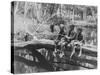 Young Boys Sitting on a Fallen Tree Spanning Small Waterhole While One Uses Homemade Fishing Pole-null-Stretched Canvas