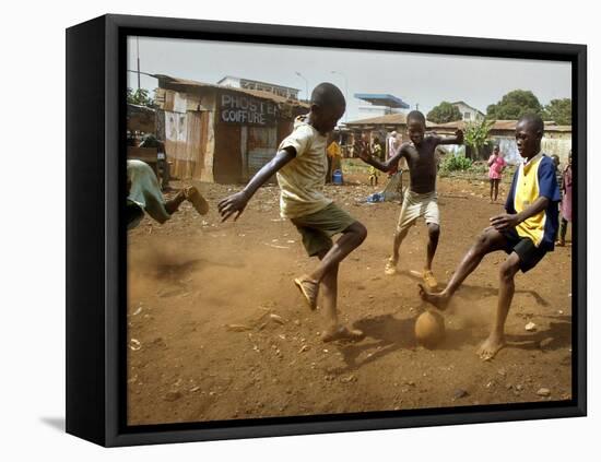 Young Children Play Soccer on a Dirt Pitch by the Side of Railway Tracks-null-Framed Stretched Canvas