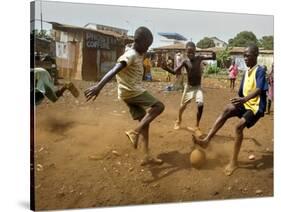 Young Children Play Soccer on a Dirt Pitch by the Side of Railway Tracks-null-Stretched Canvas