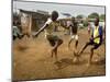 Young Children Play Soccer on a Dirt Pitch by the Side of Railway Tracks-null-Mounted Premium Photographic Print